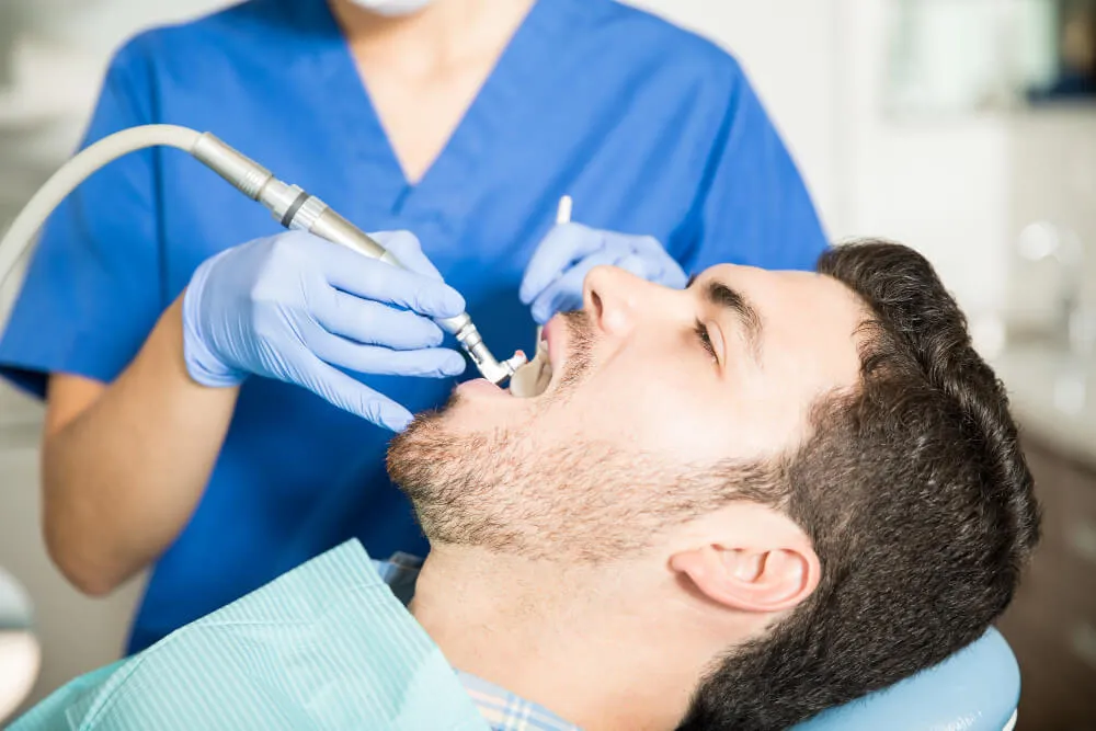 Adult man receiving dental treatment from female dentist clinic